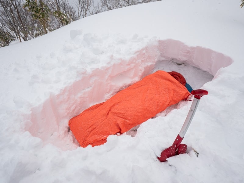 雪の中で寝袋で寝ている姿