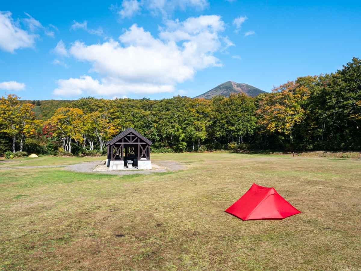 青空のキャンプ場にテントを張る