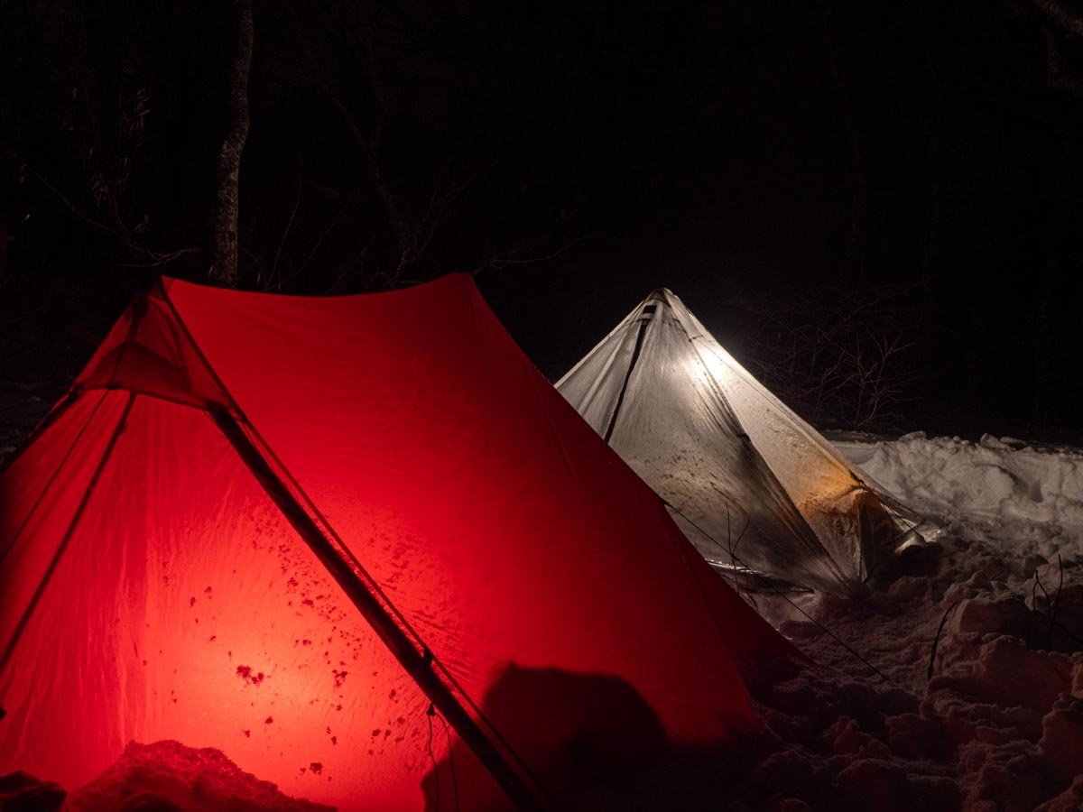 夜の雪山で光るテント