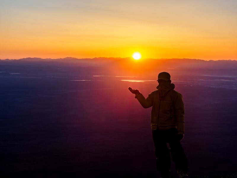 日の出の太陽を手の上に乗せる