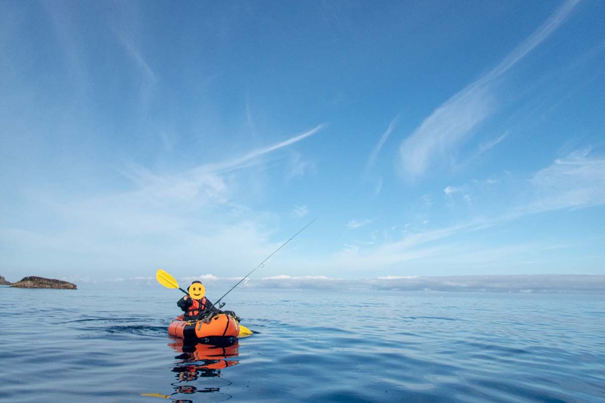 ベタ凪の海をパックラフトで釣りをしている人