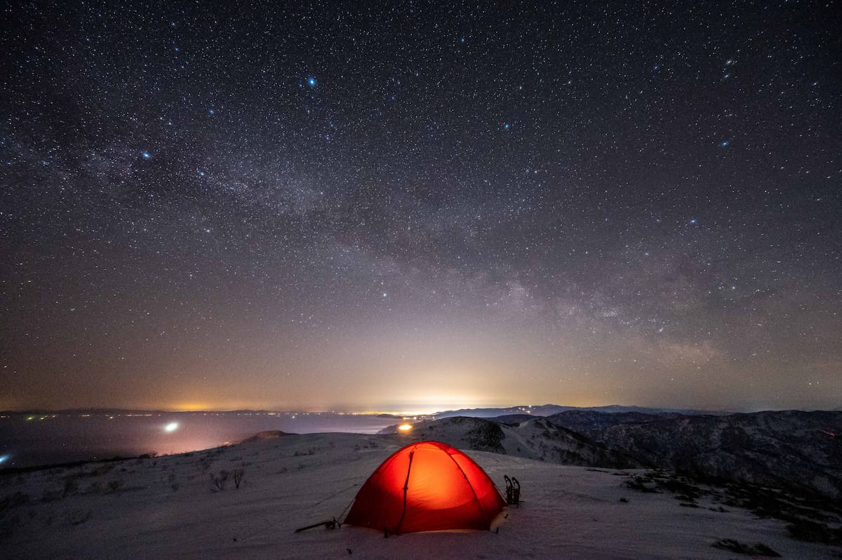 雪山で光る星空とテント